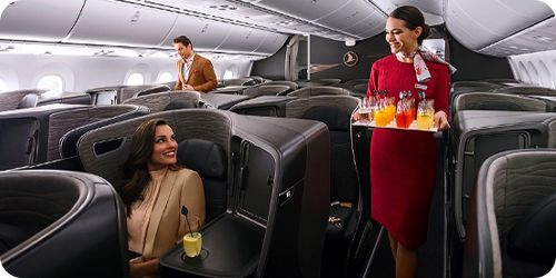 A flight attendant serves drinks to passengers in the Business Class cabin.
