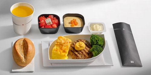 Turkish Airlines Economy Class breakfast presentation featuring an egg dish, fresh produce, warm bread, and two side dishes.