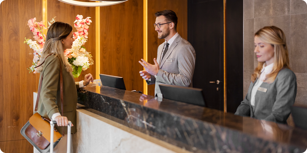 Otel'de kadın yolcuyu karşılayan 2 görevli