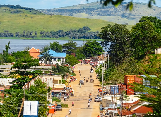 A town road in Congo showing local life, surrounded by green hills and a nearby river